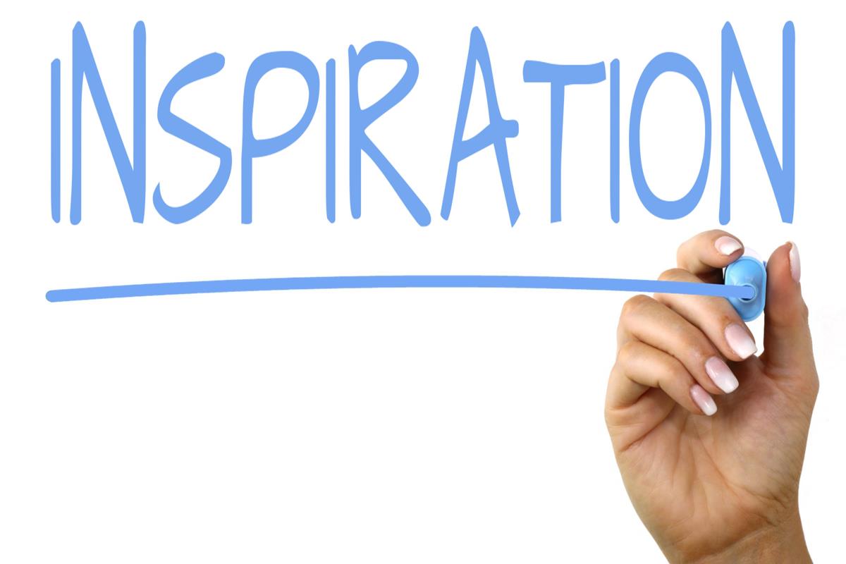 image of a hand writing the word inspiration