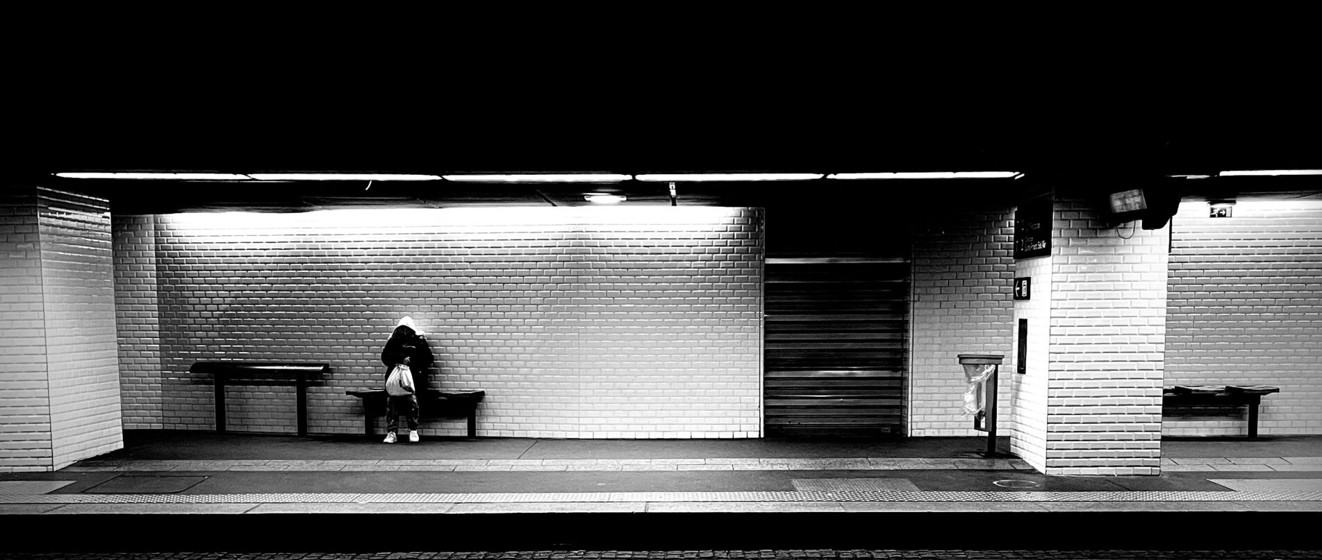 person sitting on a bench waiting for a train