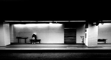 person sitting on a bench waiting for a train