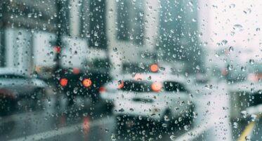 traffic seen through the window of a car dotted with rain