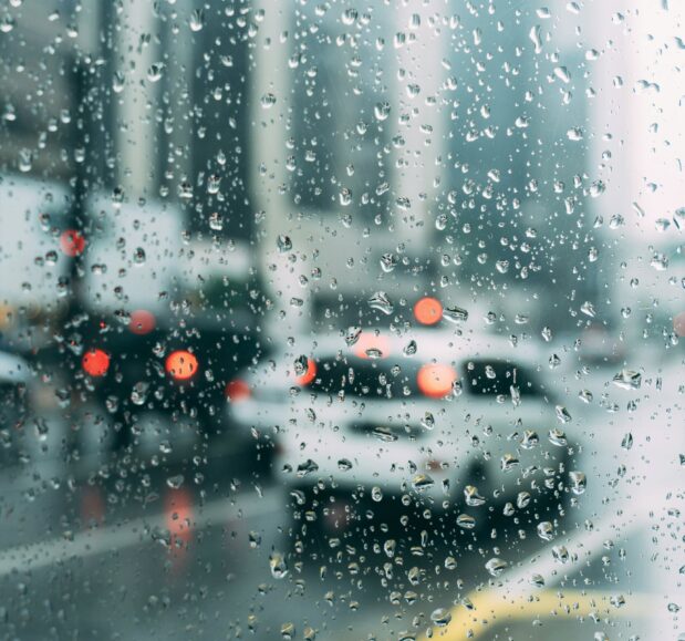 traffic seen through the window of a car dotted with rain